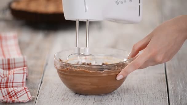 Χτυπώντας με ένα μίξερ βούτυρο με σοκολάτα. Κάνοντας κρέμα καφέ σοκολάτα για το κέικ. — Αρχείο Βίντεο
