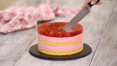 Dişi eller ahududulu krema ve jöle katmanlı tatlı pasta kesiyor..