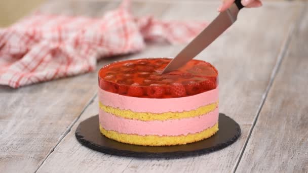 Manos femeninas cortando pastel dulce con mousse de frambuesa y capa de gelatina . — Vídeos de Stock