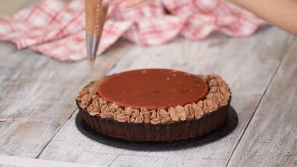 De banketbakker versiert heerlijke chocoladetaart met kersenconfit en chocoladecrème. — Stockvideo