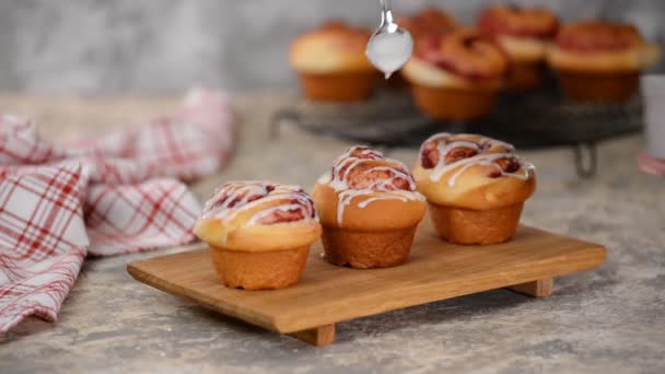 Pouring icing over swirl buns with jam. — Stock Video