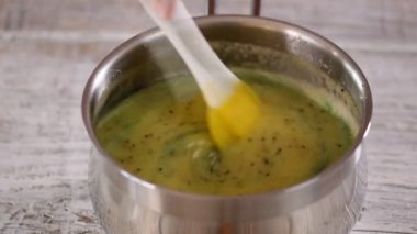 Yakın plan. Pasta şefi jöle yapmak için kivi püresi karıştırıyor..