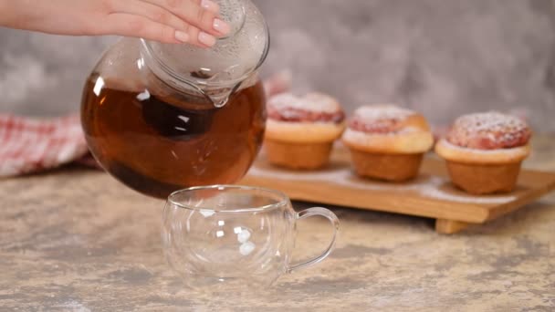 Despeje chá quente em copo de vidro. Uma xícara de chá com pães de rosas, pães doces com açúcar em pó . — Vídeo de Stock