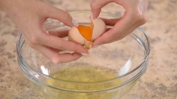 Manos femeninas rompiendo un huevo y separando la yema de la clara . — Vídeos de Stock
