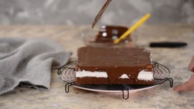 Kekin üzerine çikolata jölesi dökülüyor. Şekerci pastayı parlatır..