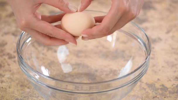 Manos femeninas rompiendo un huevo y separando la yema de la clara . — Vídeos de Stock