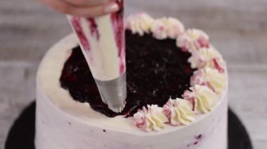 Pastayı pasta poşetinden beyaz kremayla süsleyin. Mutfakta tatlıların hazırlanması, evde şekerleme üretimi..