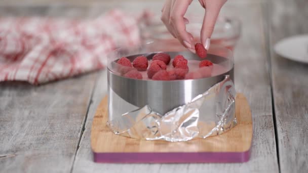 Confiseur met framboises fraîches sur un gâteau. Faire gâteau mousse framboise . — Video