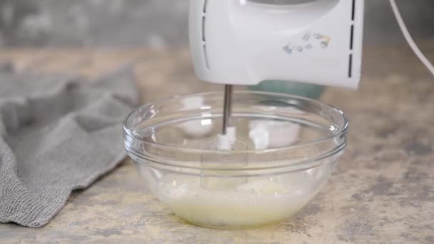 Kobieta z kuchennym mikserem bije białka jaj i posypuje cukrem. Elektryczne baterie mieszalników. — Wideo stockowe