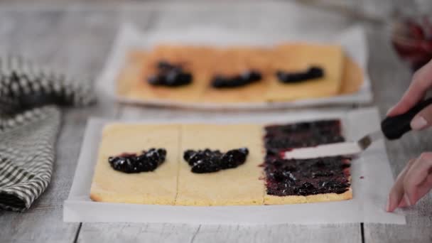 Mädchen verteilt Marmelade auf einem flachen Tortenblatt, um zu Hause einen Kuchen mit vertikalen Schichten zu backen. — Stockvideo