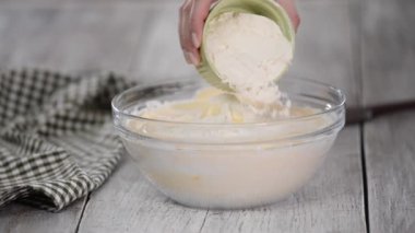 Bisküvi hamuru hazırlama işlemi. Kadın kaseye un ekliyor..