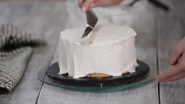 Bir şekerci kremalı pasta hazırlar. Mutfaktaki beyaz masada tatlı. Ev yapımı, kek pişirme konsepti.