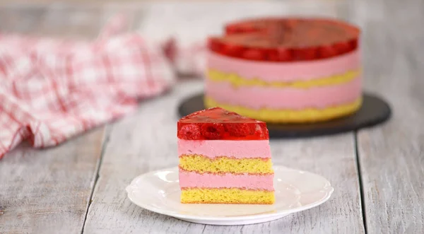 Pièce de gâteau avec biscuit à la vanille, mousse de framboise et gelée, pâtisseries sucrées . — Photo