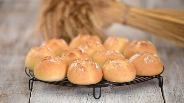 Heerlijke vers gebakken gistbroodjes met korst op koelrek. — Stockfoto