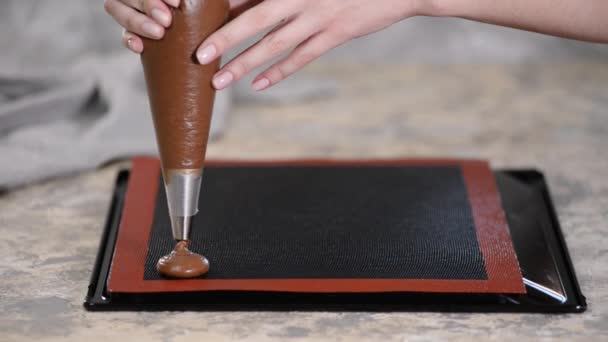 Cozinhar profiteroles de chocolate, as mãos femininas espremer a massa do saco para assar folha . — Vídeo de Stock