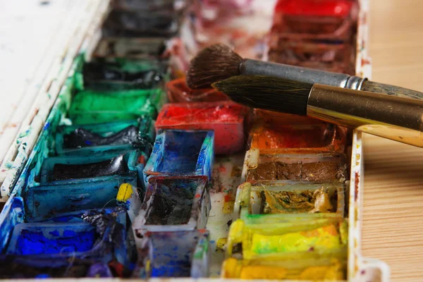 Artists brushes and watercolour paints on palette — Stock Photo, Image