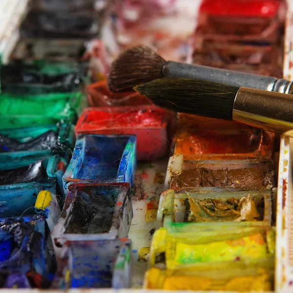 Artists brushes and watercolour paints on palette — Stock Photo, Image