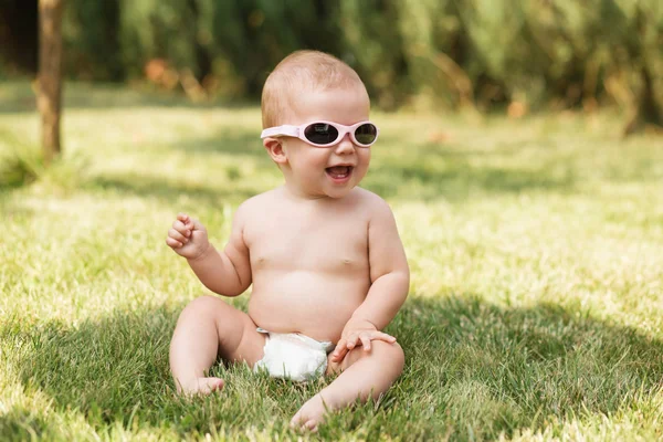 Beautiful baby sitting on green grass outdoors — Stock Photo, Image