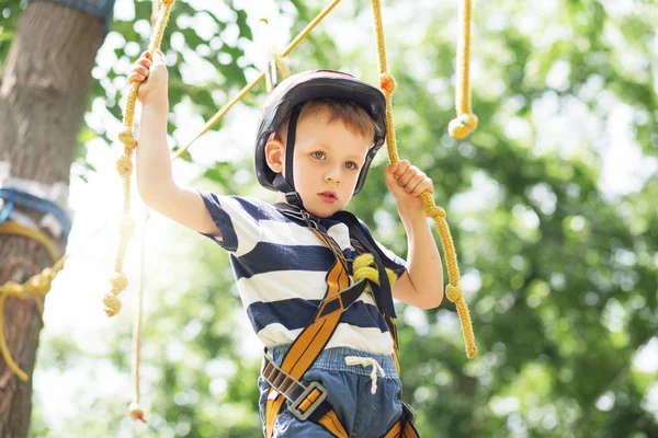 Barnen klättrar i äventyrsparken. Pojke har klättring i repet — Stockfoto