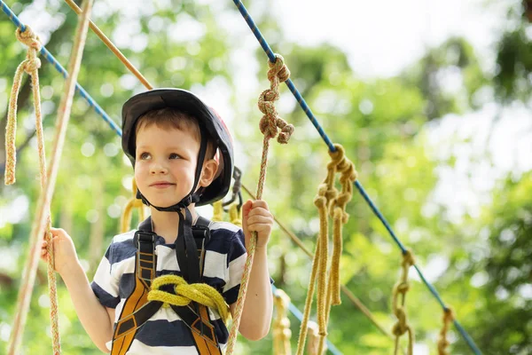 Děti v parku dobrodružství. Chlapec stojí horolezecké lano — Stock fotografie