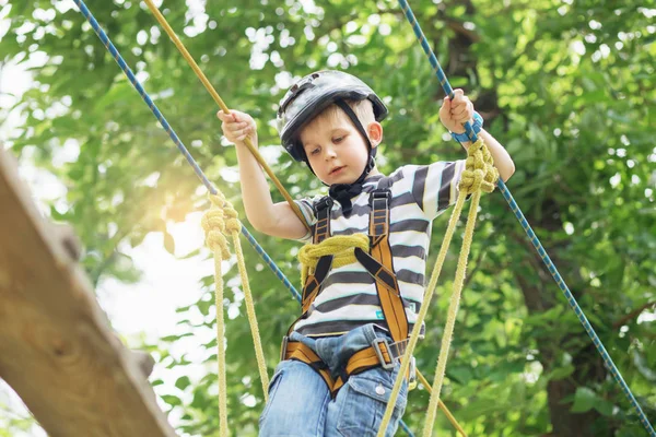 साहसिक पार्क में चढ़ने वाले बच्चे। लड़का रस्सी में चढ़ाई का आनंद लेता है — स्टॉक फ़ोटो, इमेज