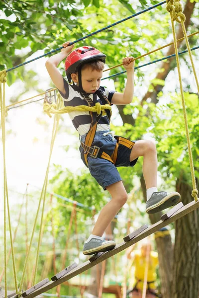 Crianças escalando no parque de aventuras. Rapaz gosta de escalar na corda — Fotografia de Stock