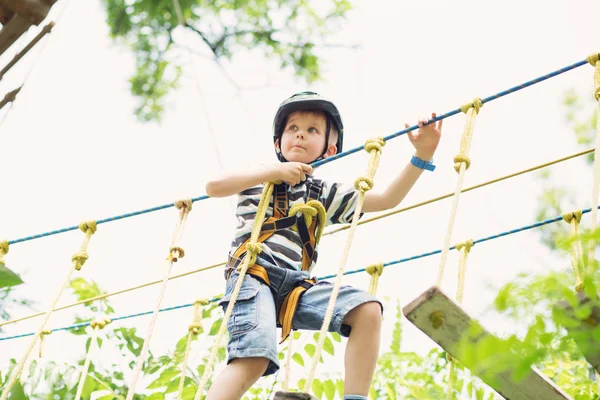 Wspinaczka w parku rozrywki dla dzieci. Chłopak cieszy się wspinaczka w liny — Zdjęcie stockowe