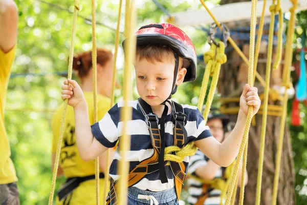 Děti v parku dobrodružství. Chlapec stojí horolezecké lano — Stock fotografie