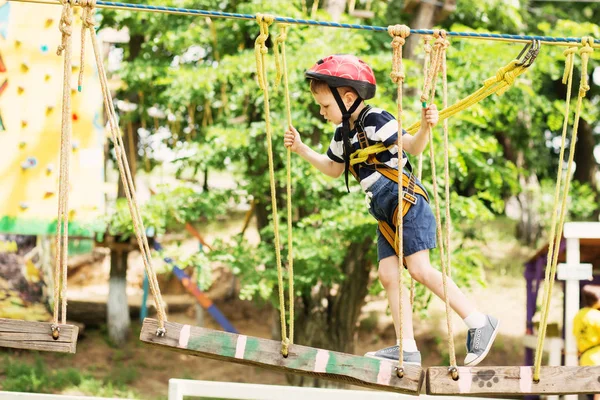 Kinderen klimmen in een avonturenpark. Jongen geniet klimmen in het touw — Stockfoto