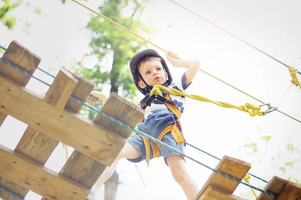 Kids climbing in adventure park. Boy enjoys climbing in the rope — Stock Photo, Image