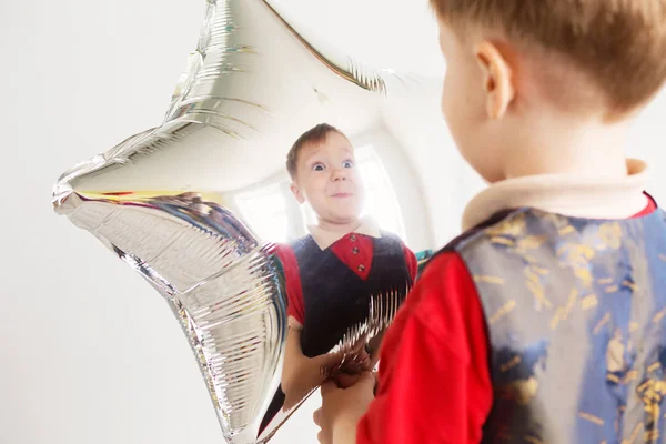 Niño riendo mirando el reflejo en un espejo distorsionado —  Fotos de Stock