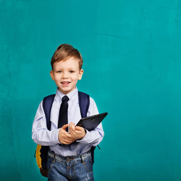 Veselý usměvavý chlapeček s velkým batohem drží digitální ta — Stock fotografie