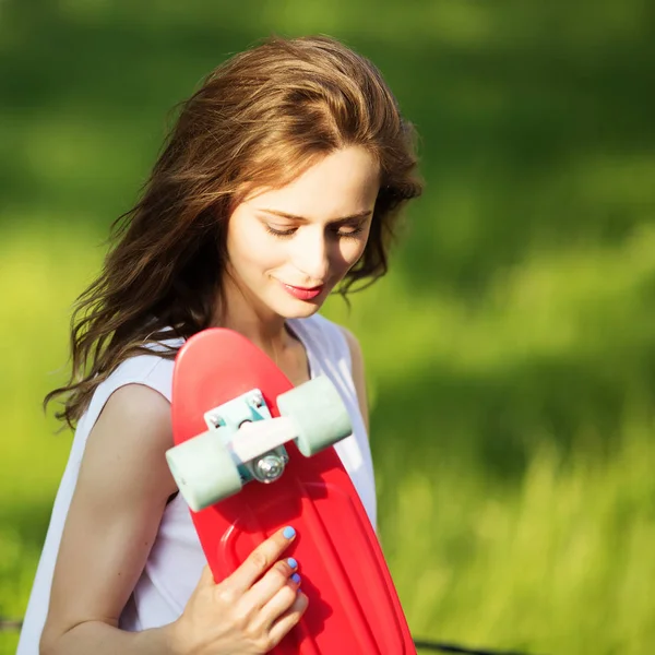 Девушка держит пластиковую скейтборд на открытом воздухе — стоковое фото