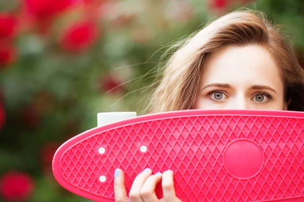 Bella ragazza urbana con uno skateboard rosa — Foto Stock