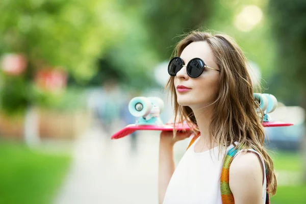 Flicka som håller en plast skate board utomhus — Stockfoto