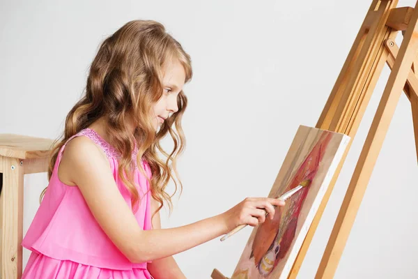 Portrait d'une jolie petite fille peignant un tableau dans un studio — Photo