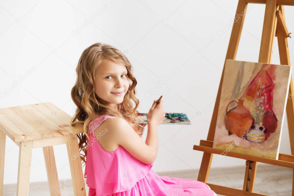 Portrait of a lovely little girl painting a picture in a studio 