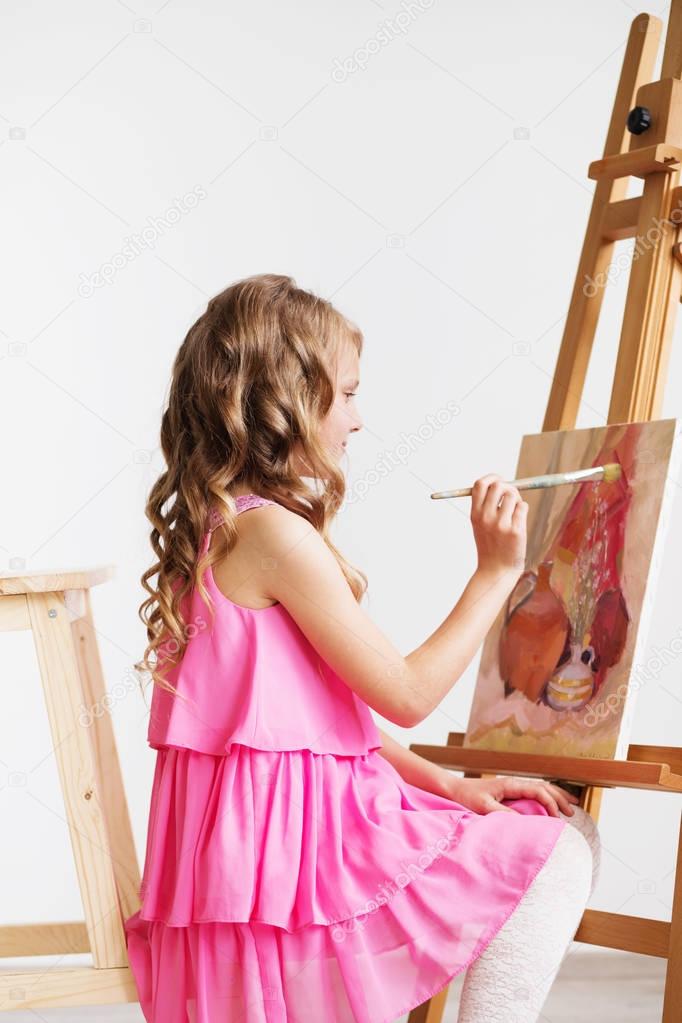 Portrait of a lovely little girl painting a picture in a studio 