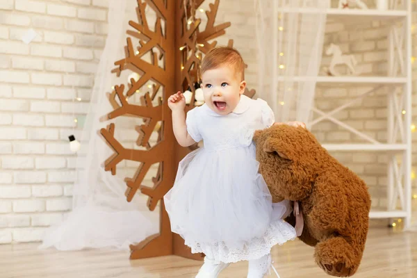 Hermosa niña con un oso de peluche marrón suave en el interior —  Fotos de Stock