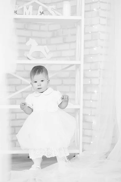 Beautiful baby girl in a white dress in the interior with Christ — Stock Photo, Image