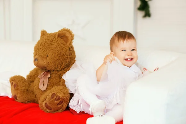 Baby girl with a soft brown teddy bear in the interior with Chri — Stock Photo, Image
