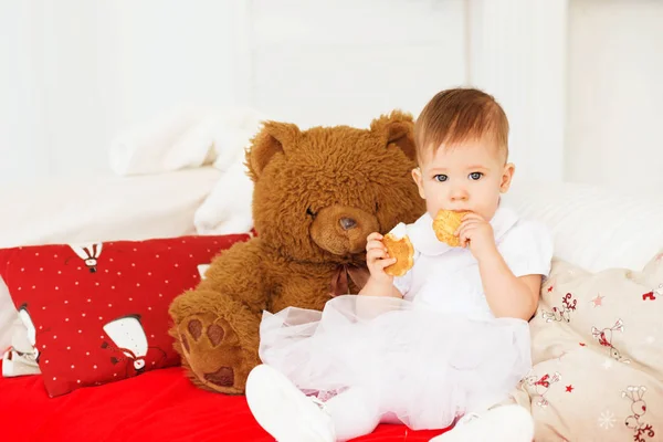 Hermosa niña con un oso de peluche marrón suave en el interior — Foto de Stock