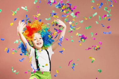 Little boy in clown wig jumping and having fun celebrating birth clipart