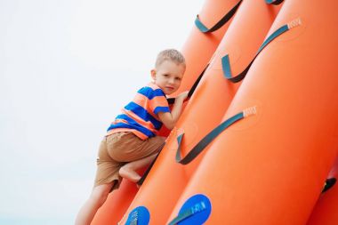 Sahilde bir şişme oyun oynayan küçük çocuk