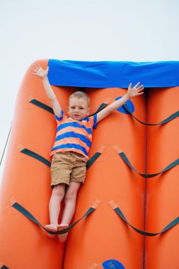 Sahilde bir şişme oyun oynayan küçük çocuk