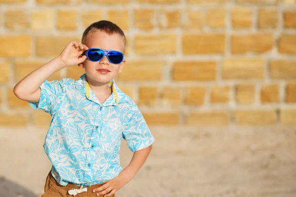 Menino vestindo óculos de sol espelho azul contra o bri amarelo — Fotografia de Stock