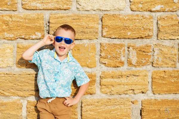 Menino vestindo óculos de sol espelho azul contra o bri amarelo — Fotografia de Stock