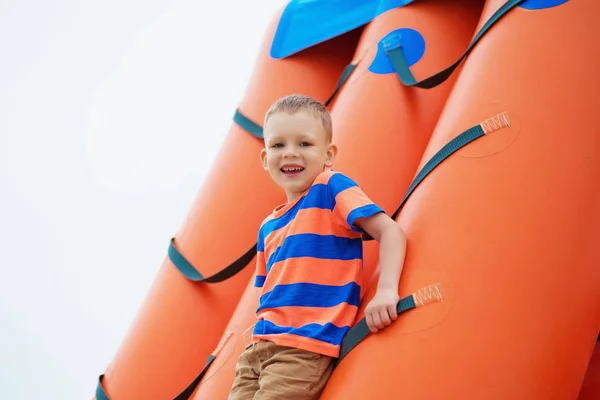 Menino brincando em um playground inflável na praia — Fotografia de Stock