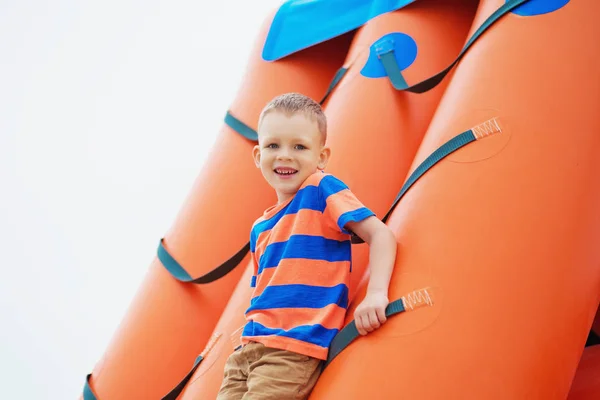 Liten pojke som spelar på en uppblåsbar lekplats på stranden — Stockfoto