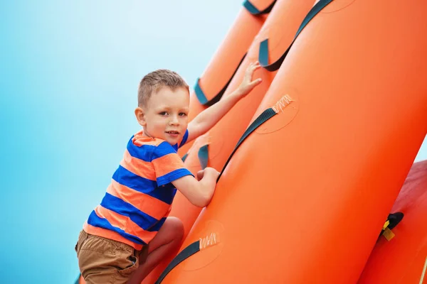 Chłopak gra na nadmuchiwany plac zabaw na plaży na letnie — Zdjęcie stockowe